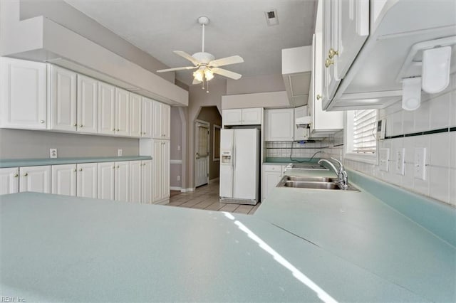 kitchen with white fridge with ice dispenser, white cabinetry, sink, light tile patterned flooring, and ceiling fan