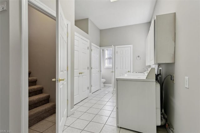 clothes washing area with cabinets, light tile patterned flooring, and washer / clothes dryer