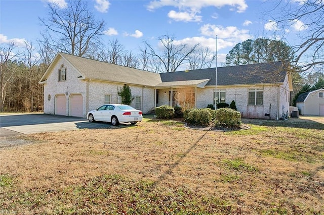 single story home featuring a garage, a front yard, and central AC unit