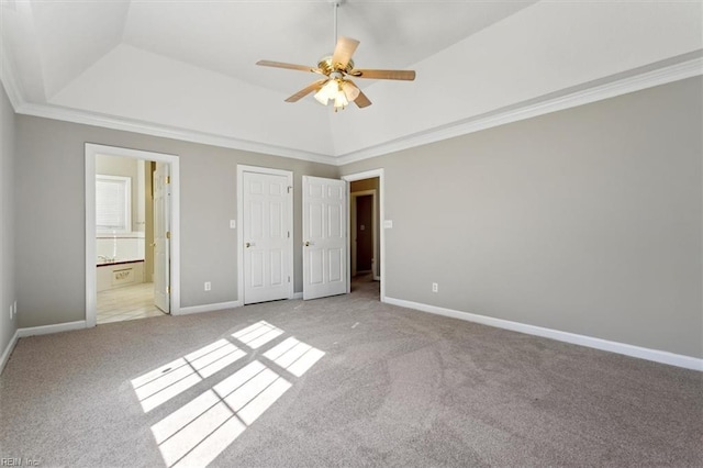 unfurnished bedroom featuring light carpet, ornamental molding, a raised ceiling, ceiling fan, and ensuite bathroom