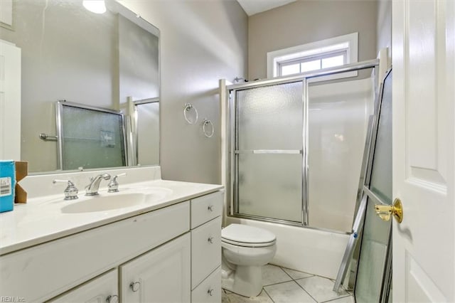 full bathroom with bath / shower combo with glass door, toilet, vanity, and tile patterned flooring