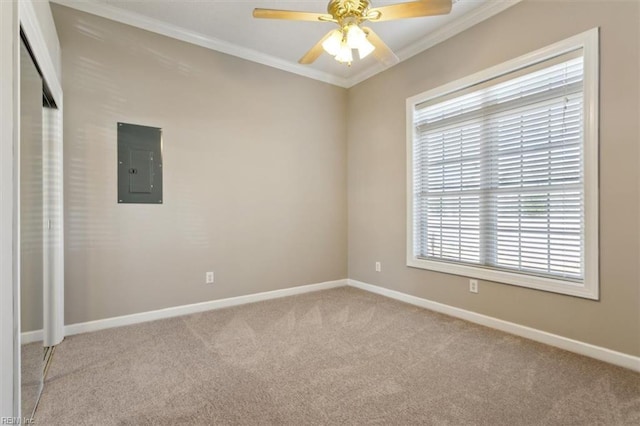 carpeted spare room featuring ceiling fan, electric panel, and crown molding