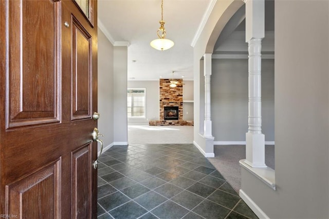 carpeted foyer with crown molding, ornate columns, and a fireplace