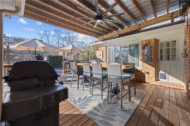 wooden deck with a mountain view, grilling area, ceiling fan, and exterior bar