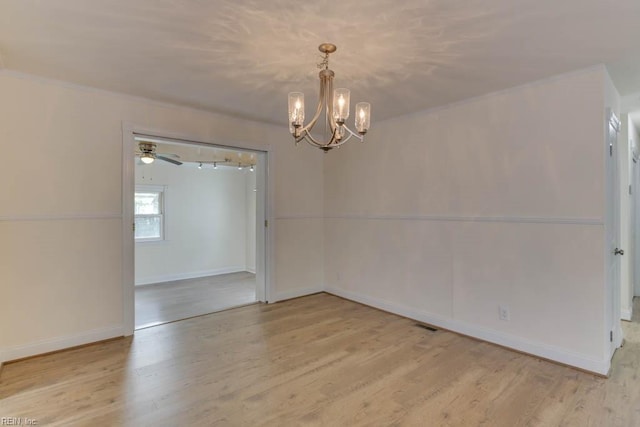 spare room featuring ceiling fan with notable chandelier and light hardwood / wood-style flooring