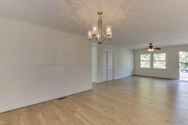 empty room with ceiling fan with notable chandelier and light hardwood / wood-style flooring