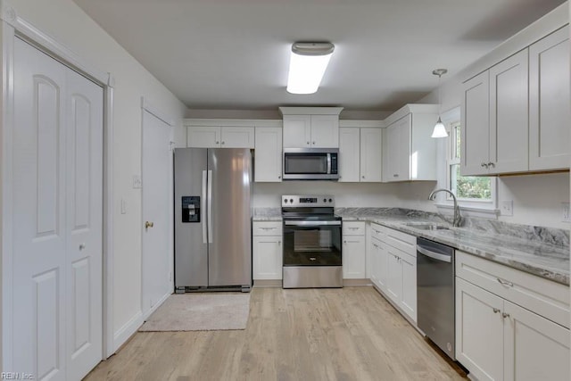 kitchen with stainless steel appliances, white cabinetry, decorative light fixtures, and sink