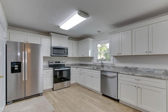 kitchen featuring light hardwood / wood-style floors, white cabinets, hanging light fixtures, and appliances with stainless steel finishes