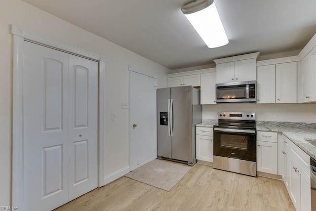 kitchen featuring light hardwood / wood-style floors, light stone countertops, stainless steel appliances, and white cabinetry