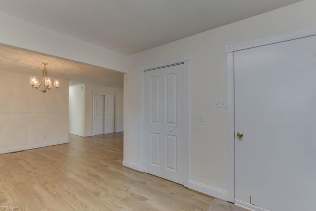 empty room featuring light wood-type flooring and an inviting chandelier