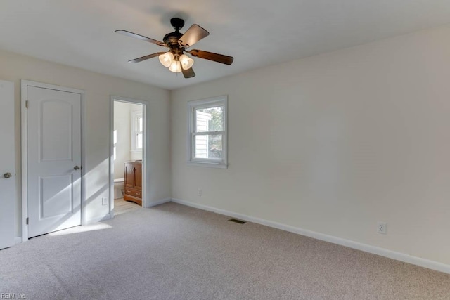 unfurnished bedroom with ceiling fan, light colored carpet, and connected bathroom