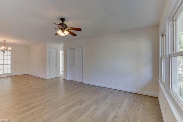 unfurnished room featuring light wood-type flooring and ceiling fan with notable chandelier