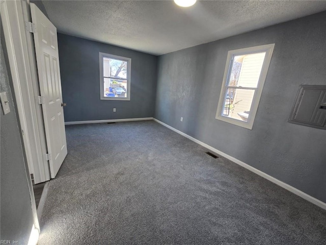 unfurnished bedroom featuring a textured ceiling and dark carpet