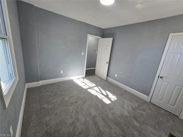 unfurnished bedroom with dark colored carpet