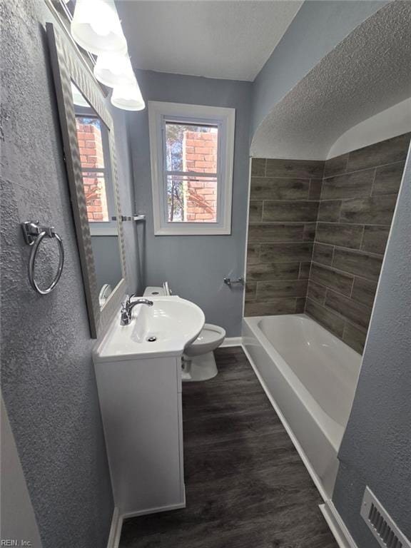 full bathroom featuring washtub / shower combination, hardwood / wood-style floors, toilet, and vanity