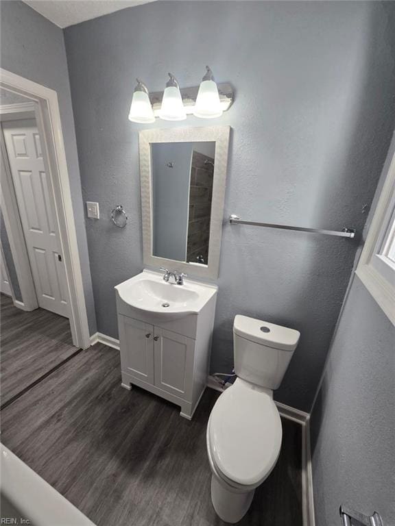 bathroom with toilet, vanity, and wood-type flooring