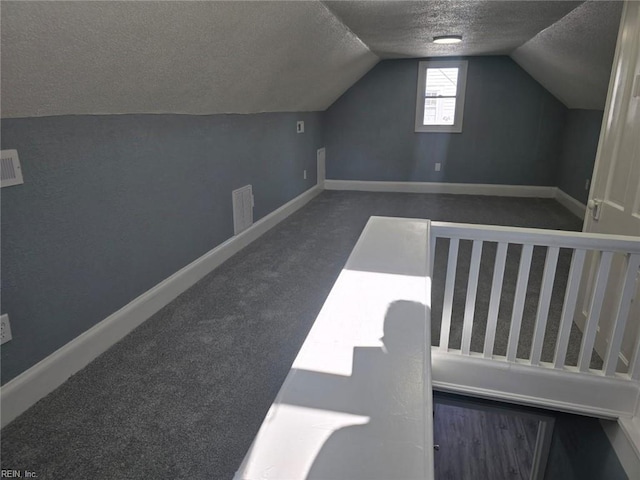 bonus room featuring dark colored carpet, a textured ceiling, and vaulted ceiling