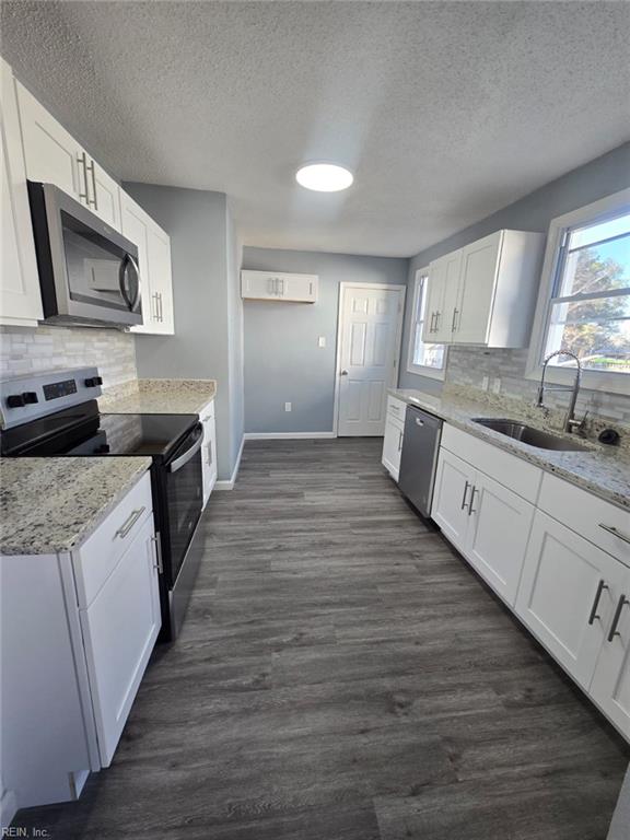 kitchen with light stone counters, sink, white cabinets, and stainless steel appliances