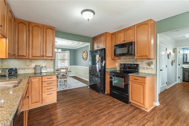 kitchen featuring decorative backsplash, dark hardwood / wood-style floors, stone countertops, black appliances, and sink