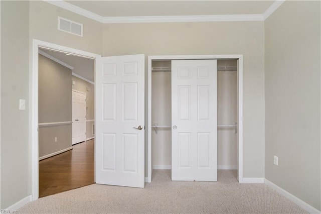 unfurnished bedroom with a closet, carpet flooring, and crown molding