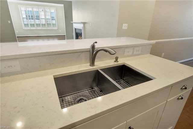 details with sink, light stone counters, and white cabinetry