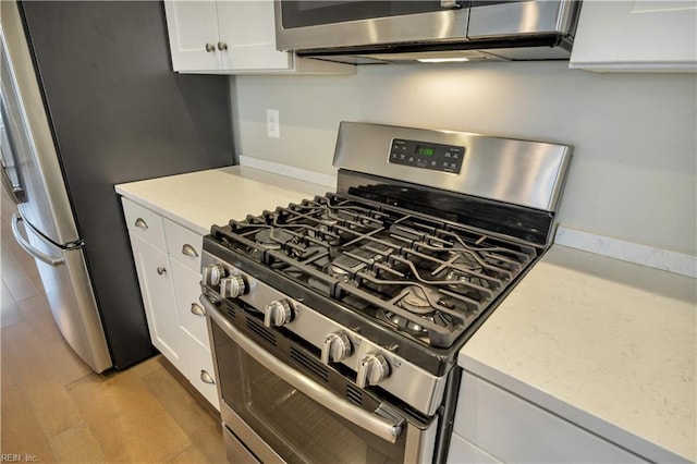 kitchen featuring light wood-type flooring, appliances with stainless steel finishes, and white cabinets