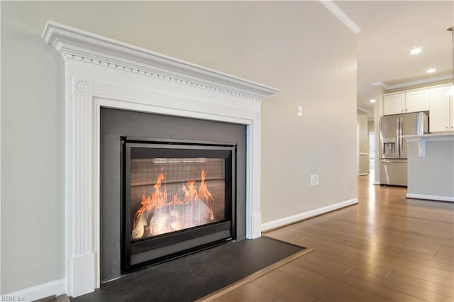 interior details with stainless steel fridge with ice dispenser, crown molding, and hardwood / wood-style floors