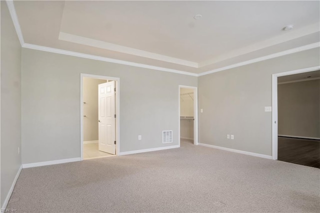 spare room with light colored carpet, a tray ceiling, and ornamental molding