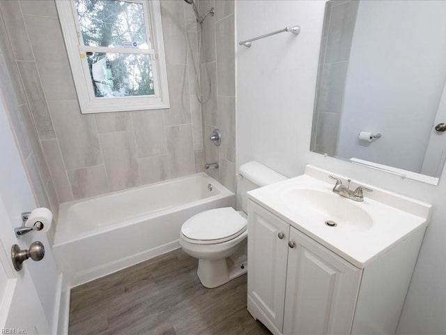 full bathroom featuring hardwood / wood-style flooring, tiled shower / bath combo, vanity, and toilet