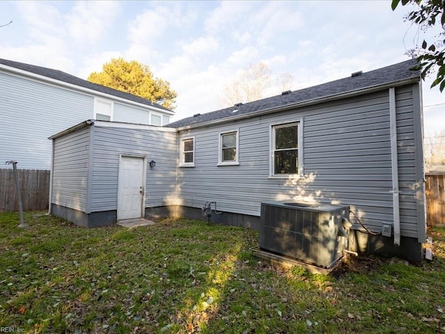 rear view of house with a lawn and cooling unit