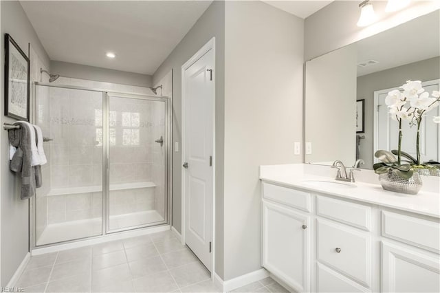 bathroom with a stall shower, vanity, baseboards, and tile patterned floors