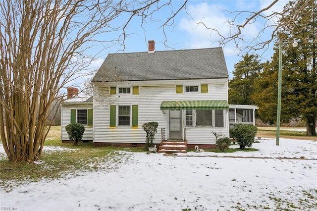 snow covered back of property featuring a sunroom