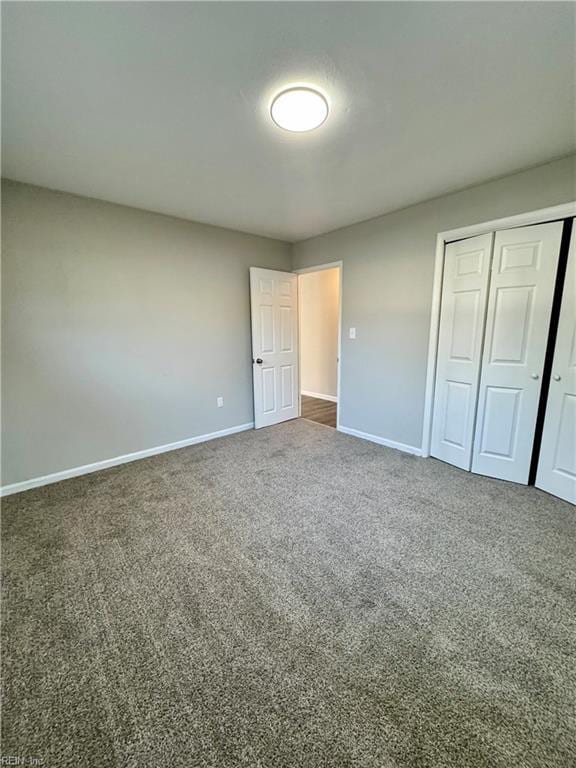 unfurnished bedroom with dark carpet and a closet