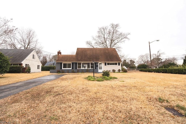 cape cod home featuring a front lawn