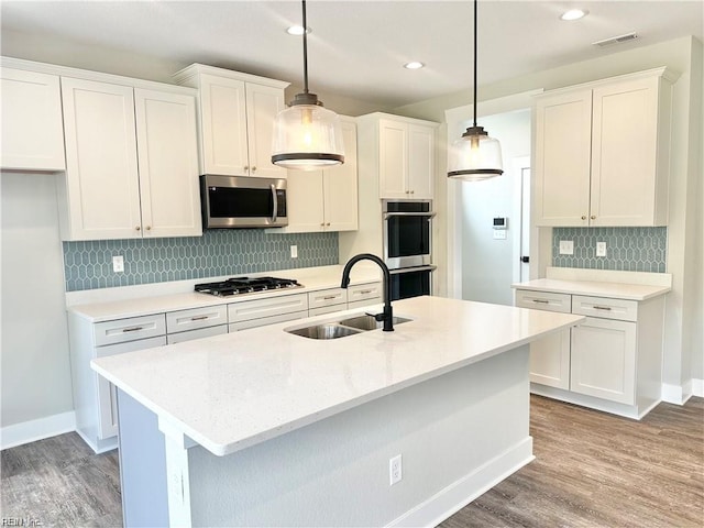 kitchen featuring white cabinets, sink, stainless steel appliances, and pendant lighting