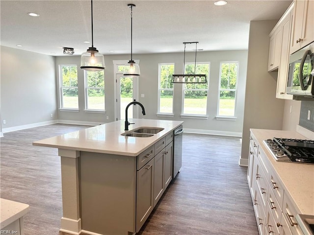 kitchen featuring decorative light fixtures, sink, an island with sink, stainless steel appliances, and white cabinets