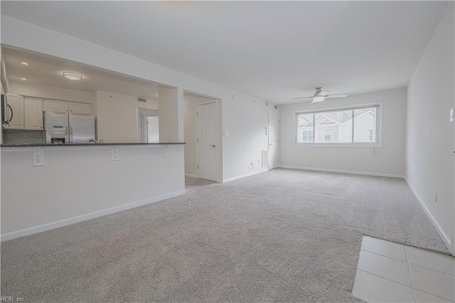 unfurnished living room featuring ceiling fan and light colored carpet