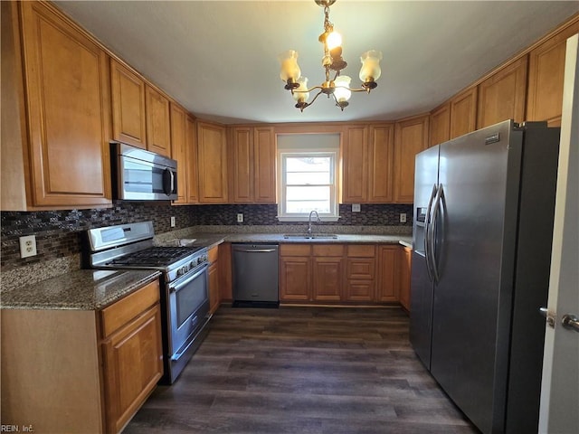 kitchen featuring a notable chandelier, sink, hanging light fixtures, appliances with stainless steel finishes, and dark wood-type flooring