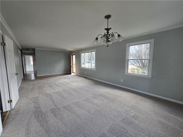 empty room featuring plenty of natural light, ornamental molding, a notable chandelier, and carpet flooring