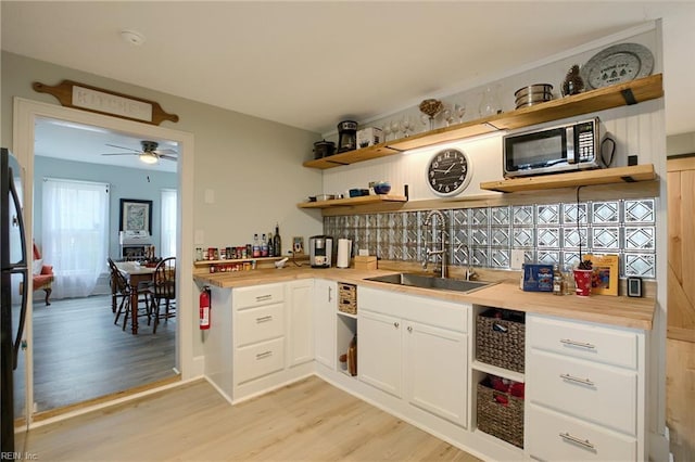 kitchen with white cabinetry, butcher block counters, light hardwood / wood-style floors, and sink