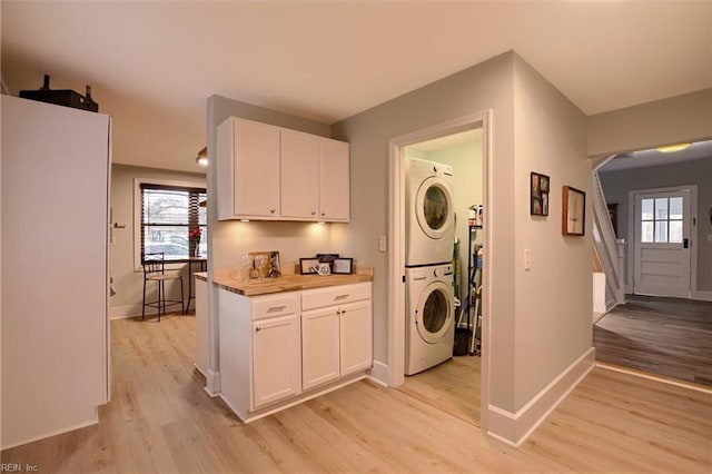 clothes washing area with stacked washer / dryer and light hardwood / wood-style flooring