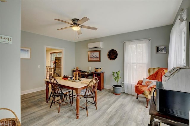 dining space featuring ceiling fan, a wall mounted AC, and light hardwood / wood-style floors