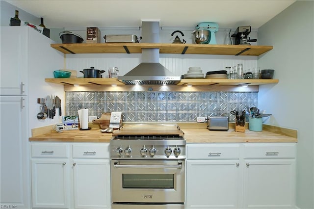 kitchen with white cabinets, high end stainless steel range, wall chimney range hood, and butcher block countertops