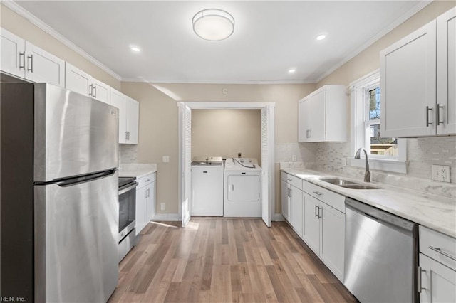 kitchen featuring sink, white cabinetry, stainless steel appliances, and washing machine and clothes dryer