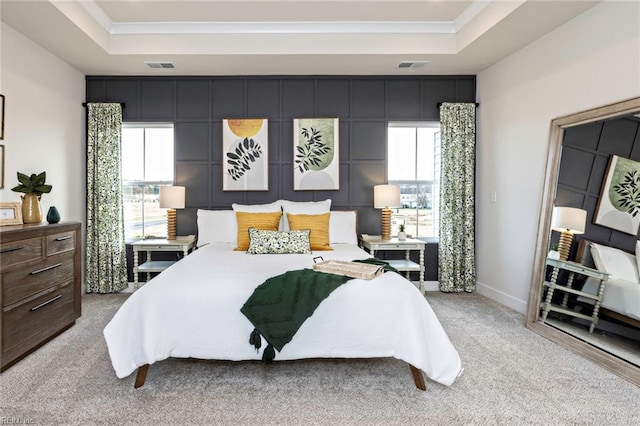 carpeted bedroom featuring crown molding and a tray ceiling