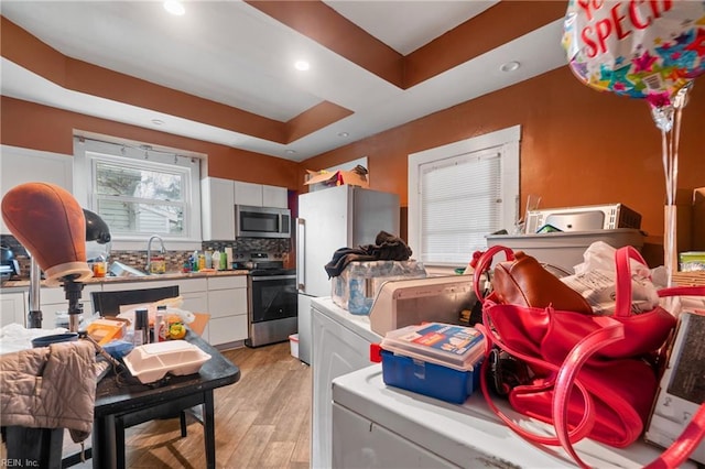 kitchen with tasteful backsplash, a raised ceiling, light hardwood / wood-style flooring, stainless steel appliances, and white cabinets