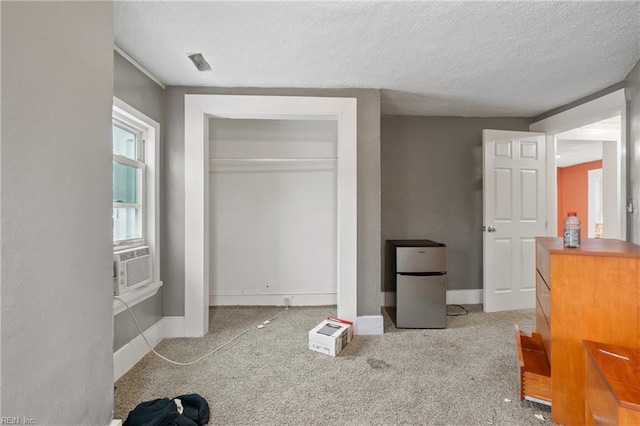 unfurnished bedroom featuring light carpet, a closet, a textured ceiling, and stainless steel refrigerator