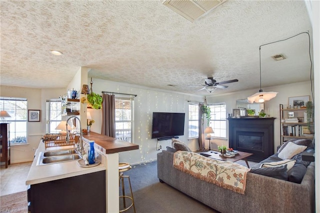 living room featuring ceiling fan, sink, and a textured ceiling