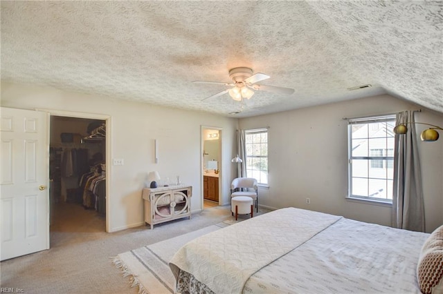 bedroom with a spacious closet, ensuite bath, a closet, vaulted ceiling, and ceiling fan