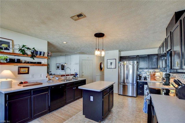 kitchen with hanging light fixtures, a textured ceiling, a kitchen island, black appliances, and sink